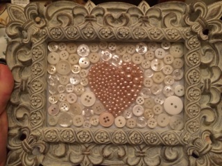 This is probably my favorite. There is white cardstock inside the frame and then I used the beads on a cheapy, pink "pearl" necklace to make a heart (I drew on the back side of the glass using a dry erase marker first to trace the heart shape), and then filled in the background with white buttons. Everything was stuck on using hot glue.